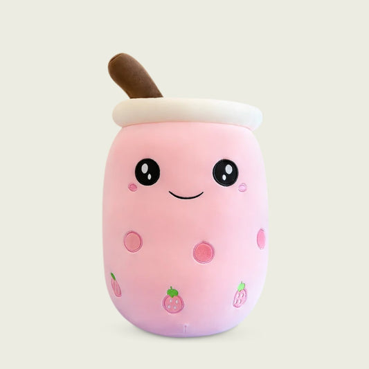 A plush toy resembling a bubble tea drink with a happy facial expression, featuring white and pink colors with brown accents and a brown straw.