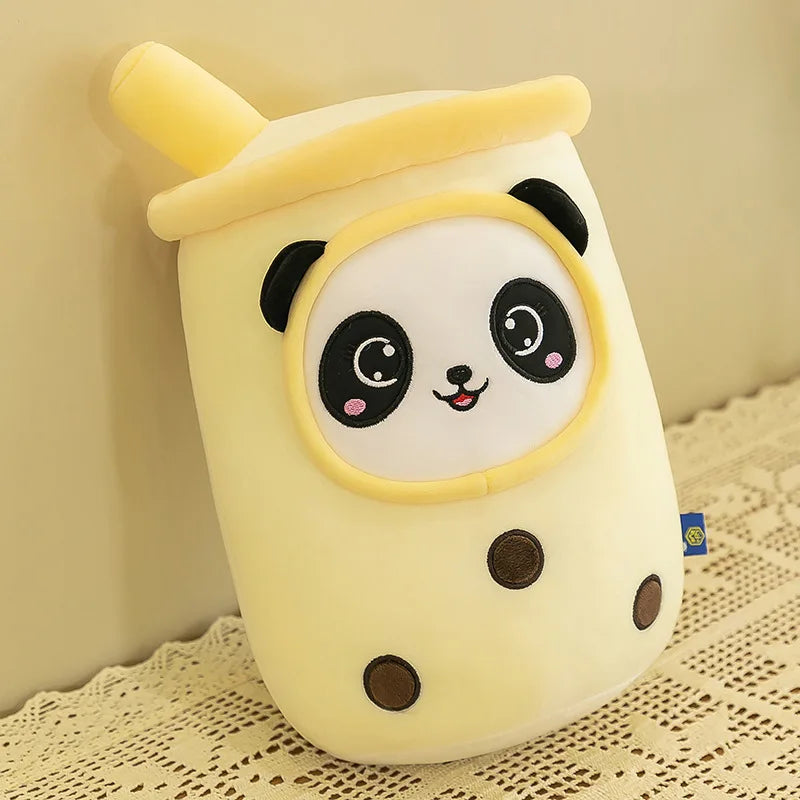 An image showing a yellow boba tea plushie with a smiling panda face and three black mochi balls