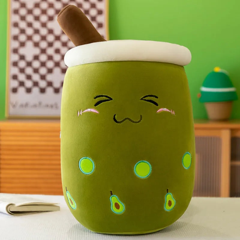 Product photo of a green boba tea plushie with a blushing face and green avocado icons