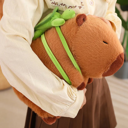 Capybara with green tortoise backpack being held under one arm by woman.