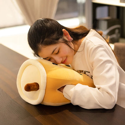 This image shows a girl lying down on a brown sugar boba tea plushie with her hands in the side holes.