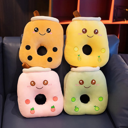 An image of four boba tea pillow plushies including a brown sugar boba, yellow pineapple bubble tea, pink strawberry milk tea, and green apple boba.