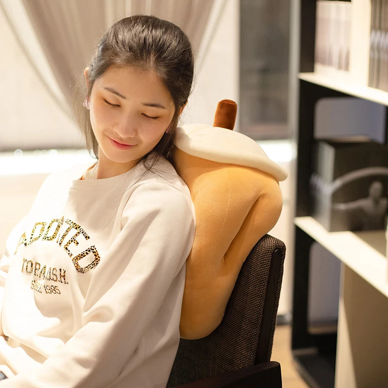The image shows a girl sitting on a chair leaning her back on the brown sugar boba tea pillow plushie closing her eyes.