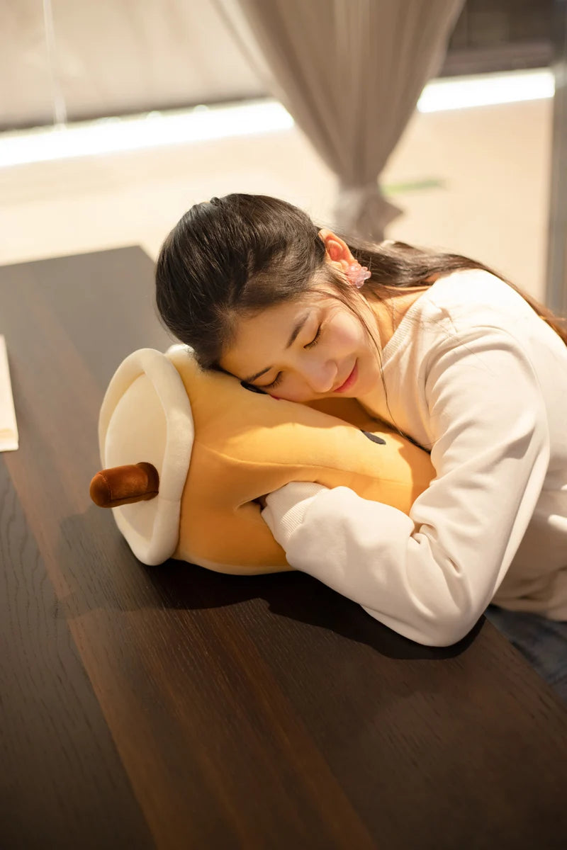 Image displaying a girl lying on the brown sugar bubble team center-hole plushie pillow on a table with her hands in the side holes.