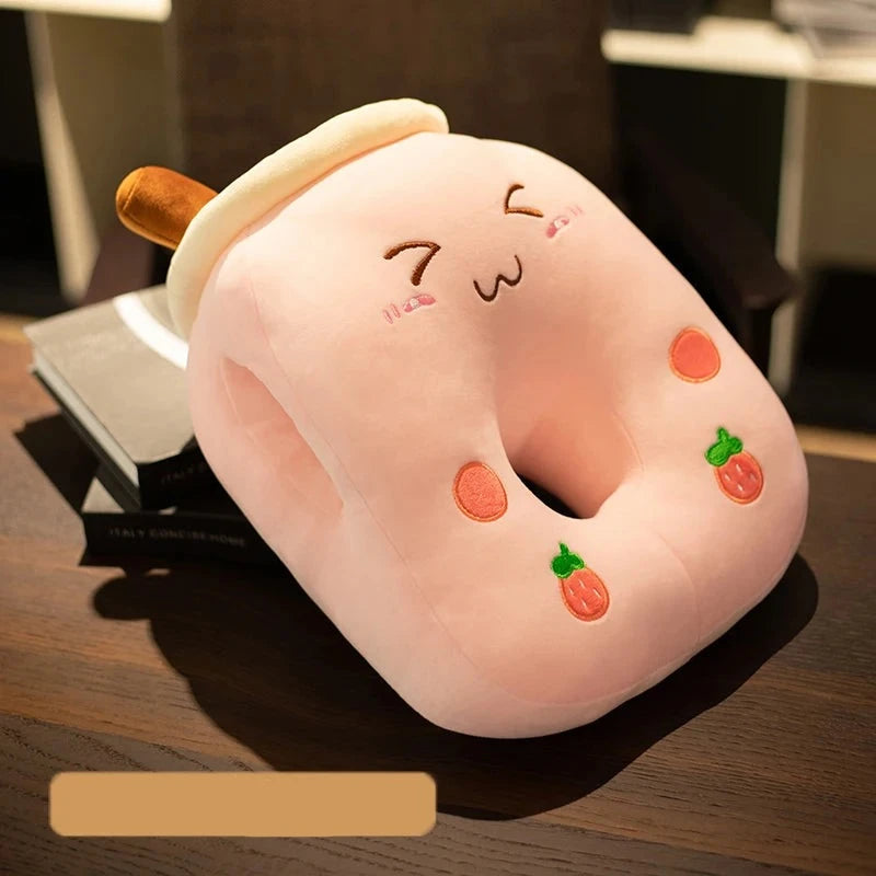 A pink pillow cushion for sleeping face down with a center hole. The pillow has a grinning face with squinted eyes, two small strawberries and two small pink circles.