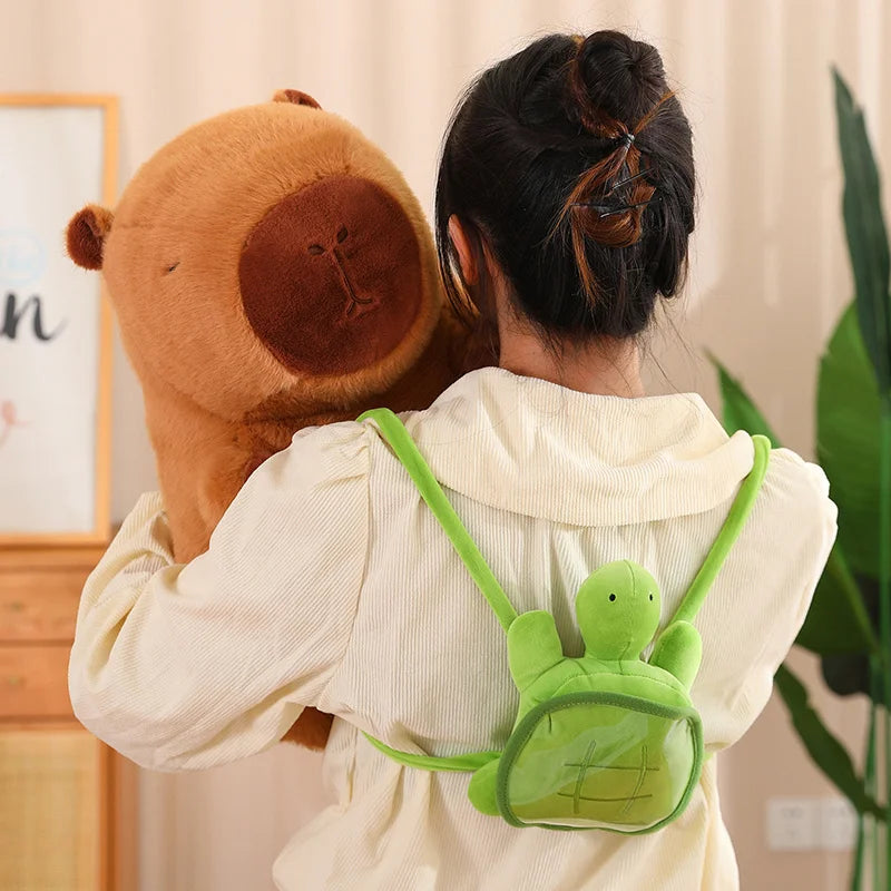 Image depicting the back of a lady wearing the capybara's green tortoise backpack and holding the large brown capybara stuffed animal in her hands.