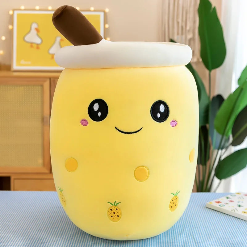 An image showing a yellow smiling bubble tea drink plushie with pineapple images on the side and a brown straw