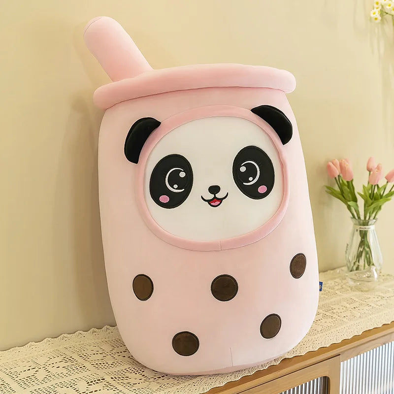 An image showing a pink bubble tea drink plushie with a smiling panda face in the middle and five black tapioca pearls inside