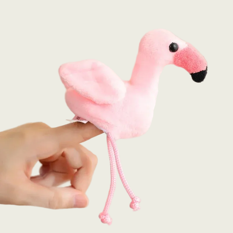 Pink flamingo plush toy held by a hand against a neutral background