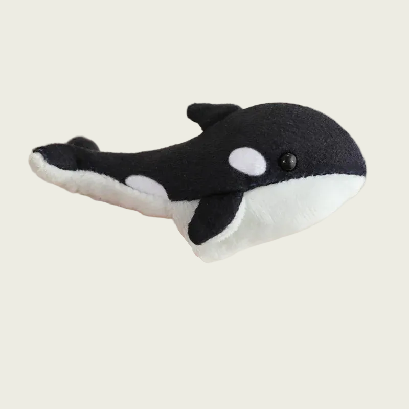 Small plush whale toy held in a hand against a plain background