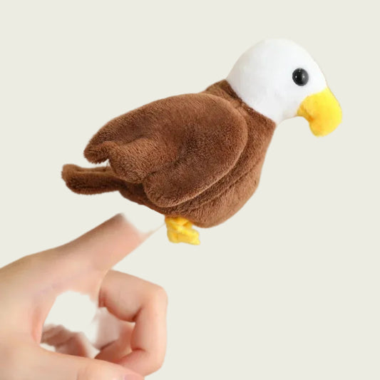 Plush toy eagle on a finger against a beige background