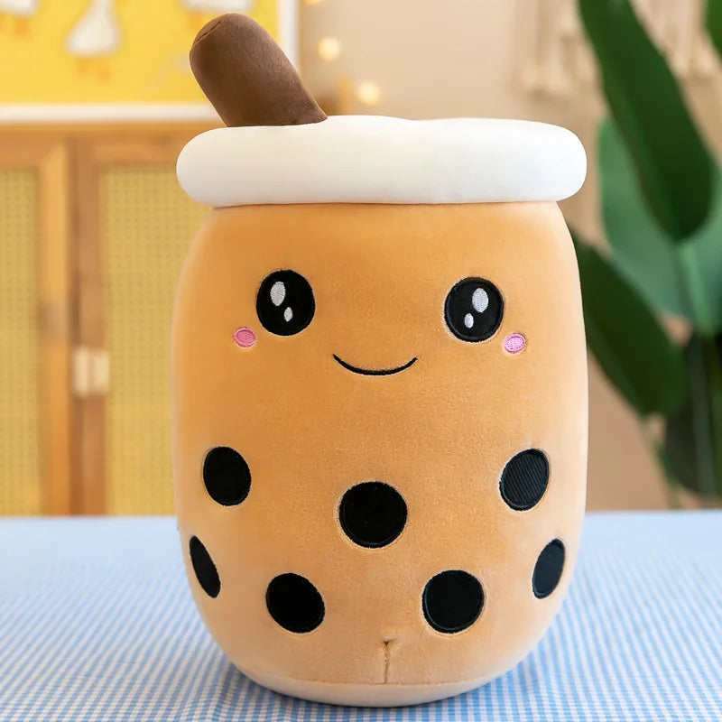 An image showing a brown sugar boba tea plushie with big black eyes, pink dimples, a black smile, and black circles representing boba tapioca pearls