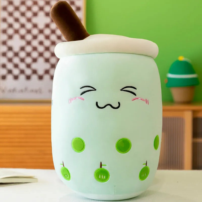 An image showing a mint green bubble tea plushie with a smiling face, green apple graphics, and a brown straw